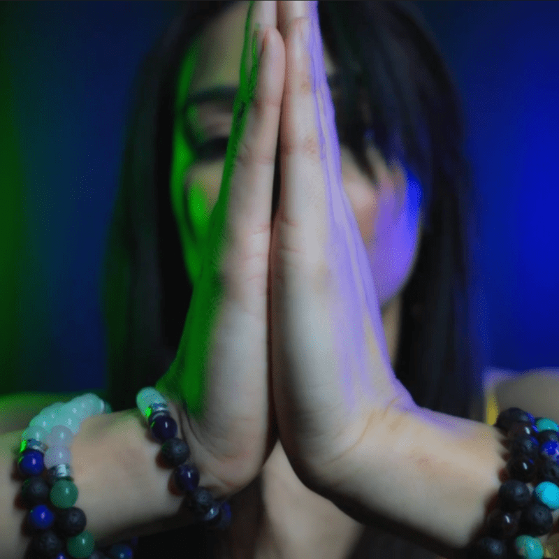 MissG holding hands up close to the camera in prayer position while wearing Alight Healing bracelets.