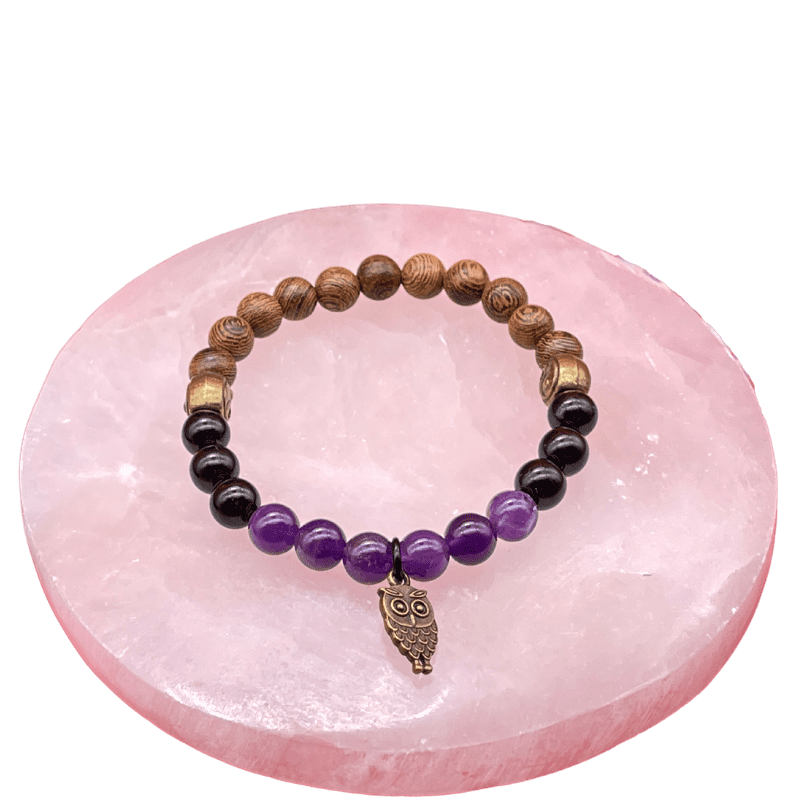 Amethyst and black tourmaline and wenge wood bracelet with an owl pendant on a selenite slab